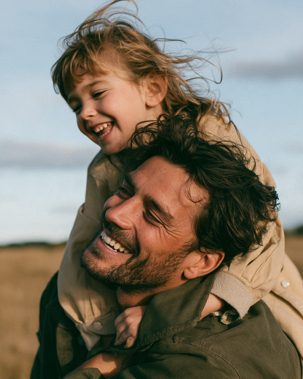 Father carrying his laughing child on his shoulders outdoors